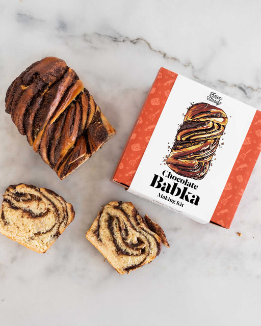 Chocolate babka with a box labeled 'Chocolate Babka Making Kit' on a marble surface