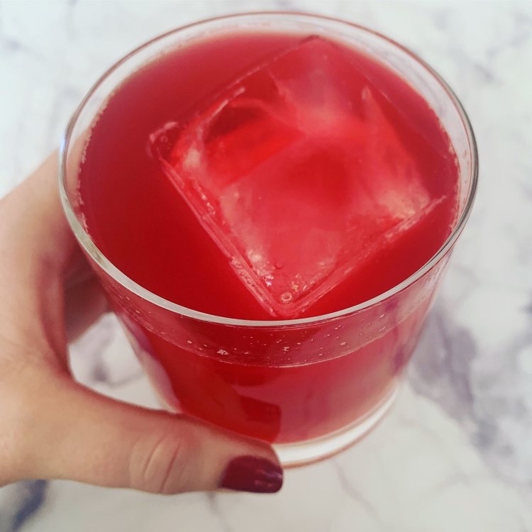Glass of ruby-red hibiscus kombucha over ice