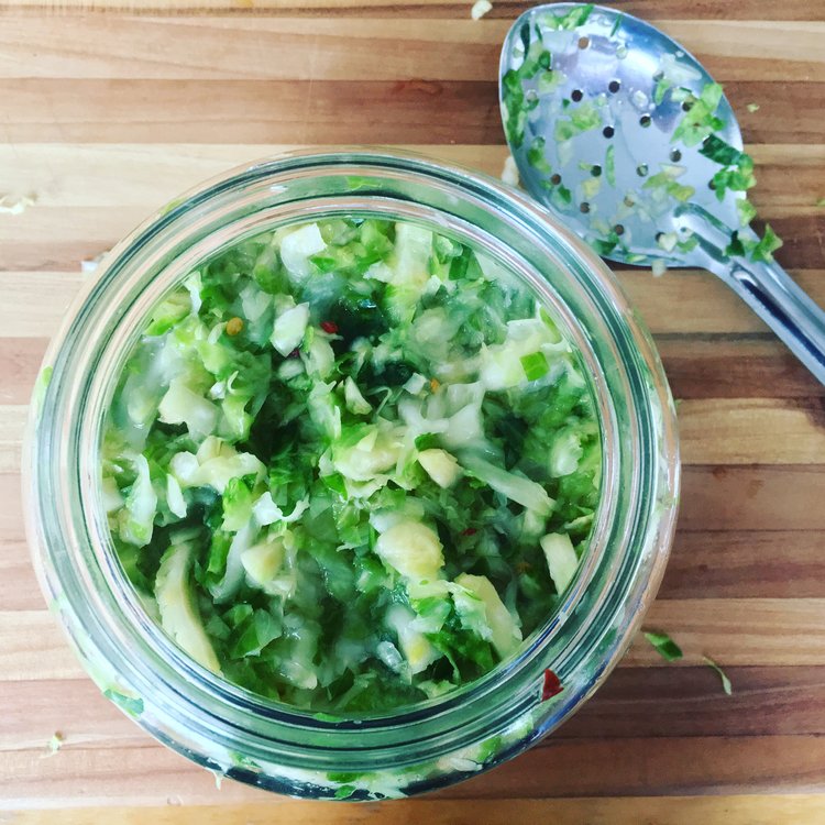 Jar of maple chili Brussels sprout kraut on a cutting board