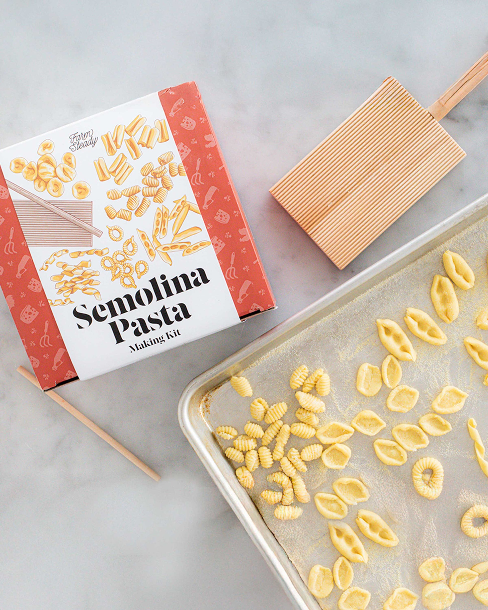 Semolina Pasta Making Kit box with gnocchi board and fresh pasta shapes on a sheet pan