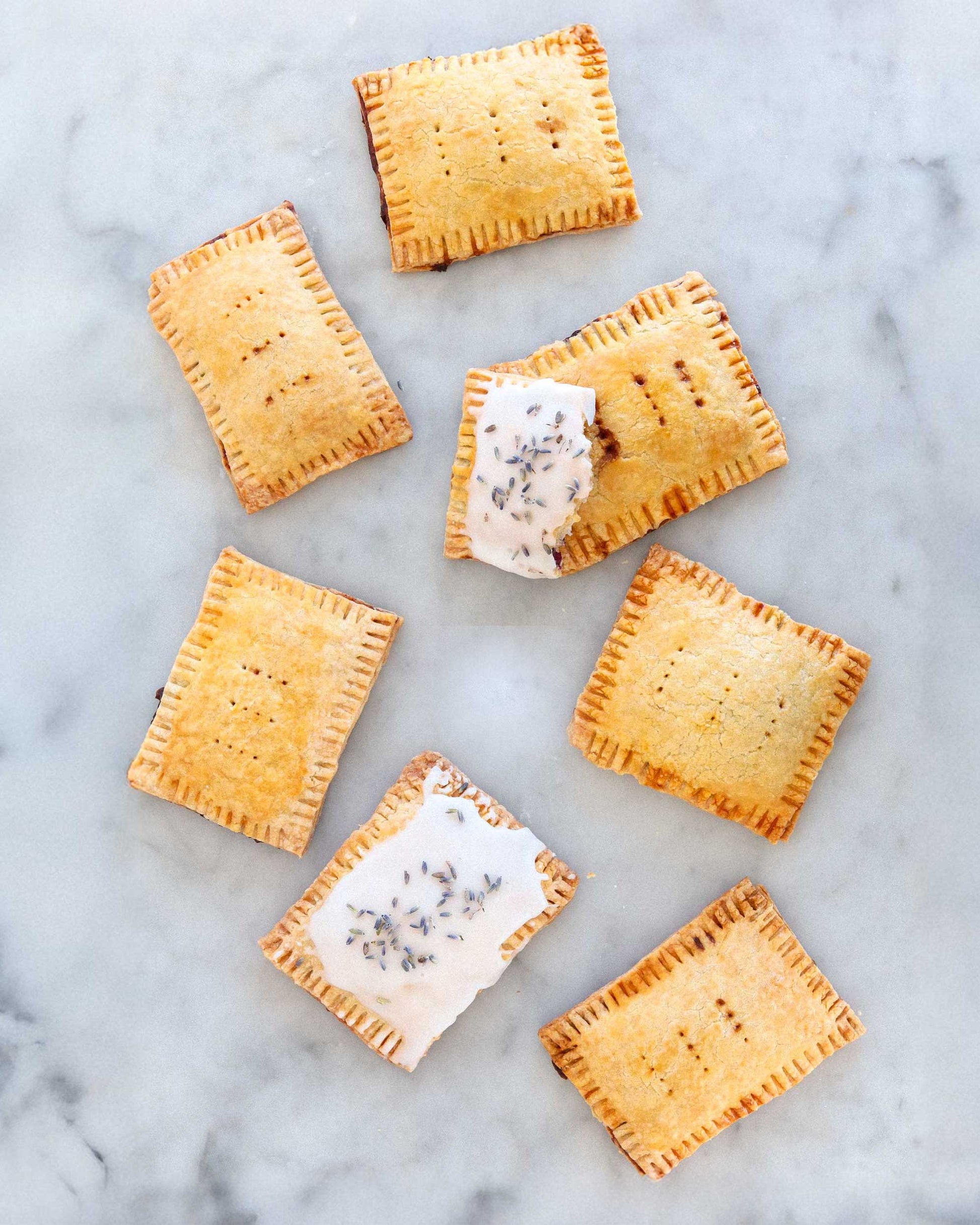 Iced pastry tarts with lavender on a marble counter