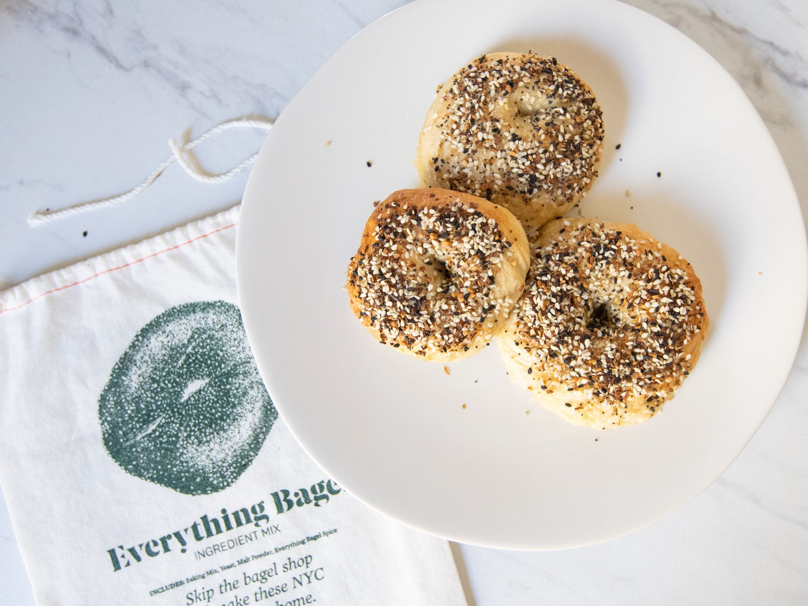 Mixed dozen of FarmSteady bagels — sesame, everything, plain, and salt — on a Brooklyn marble counter