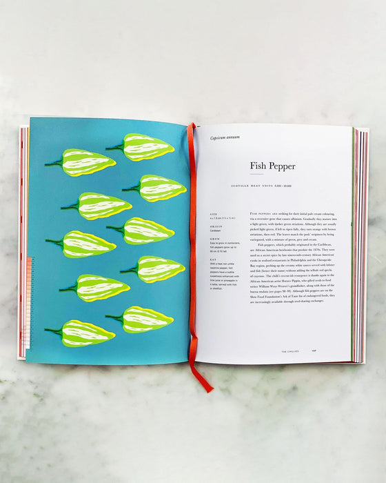 An Anarchy of Chillies book by Caz Hildebrand opened to a page on Fish Peppers, laying on marble.